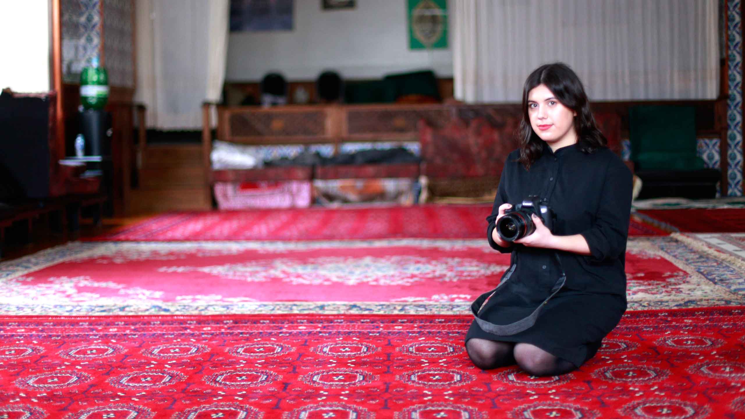 Photo of Alia Youssef kneeling with a camera