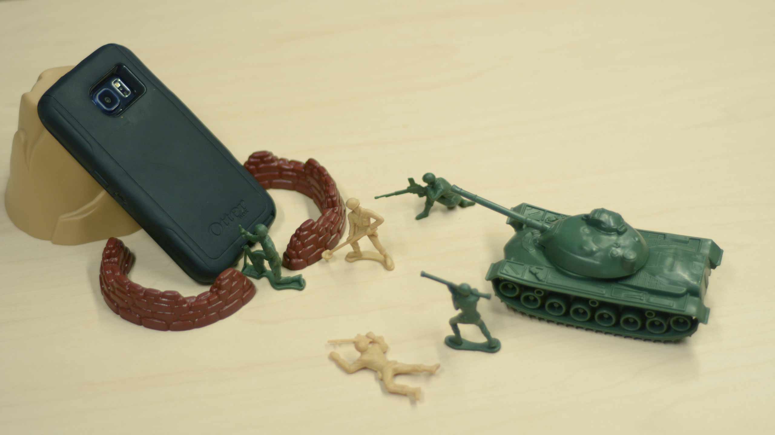 Toy army soldiers fighting a cell phone