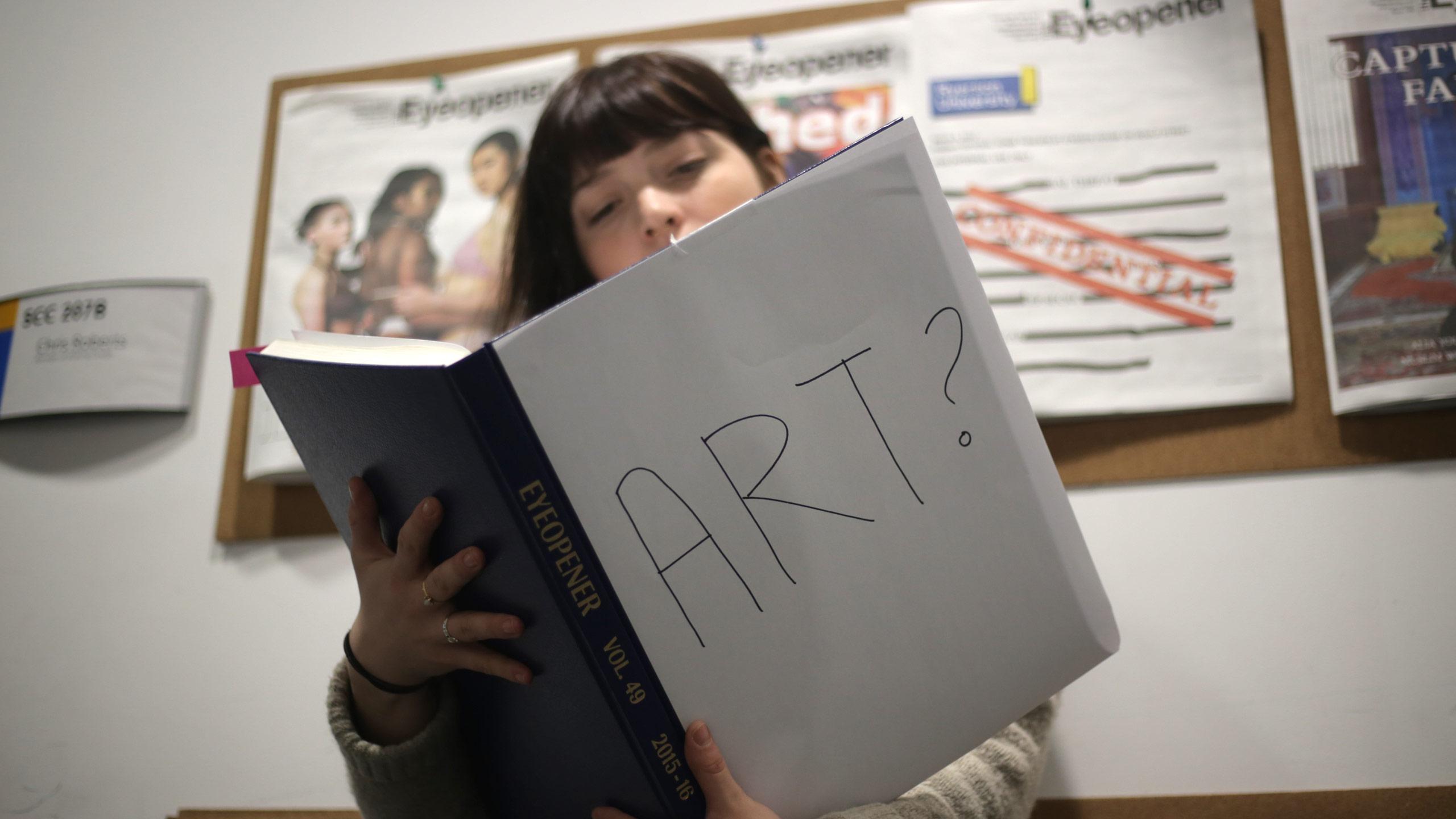 Somebody with an open book. The cover of the book reads: Art?