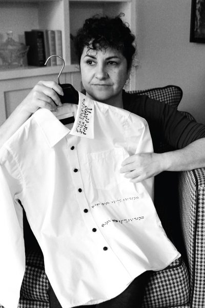 A woman holding a shirt with a braille design on it.