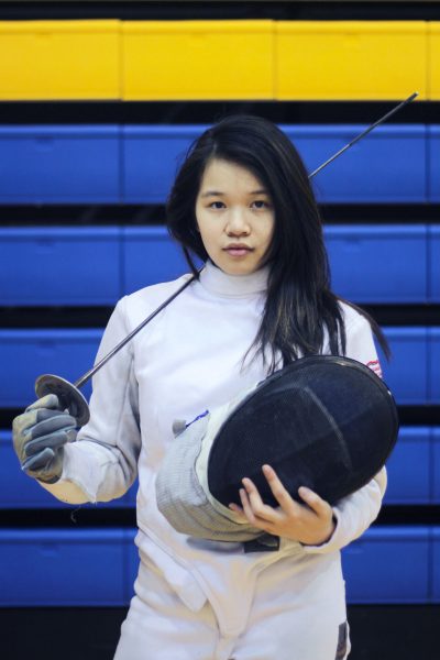 Fencer posing holding her helmet and her sword