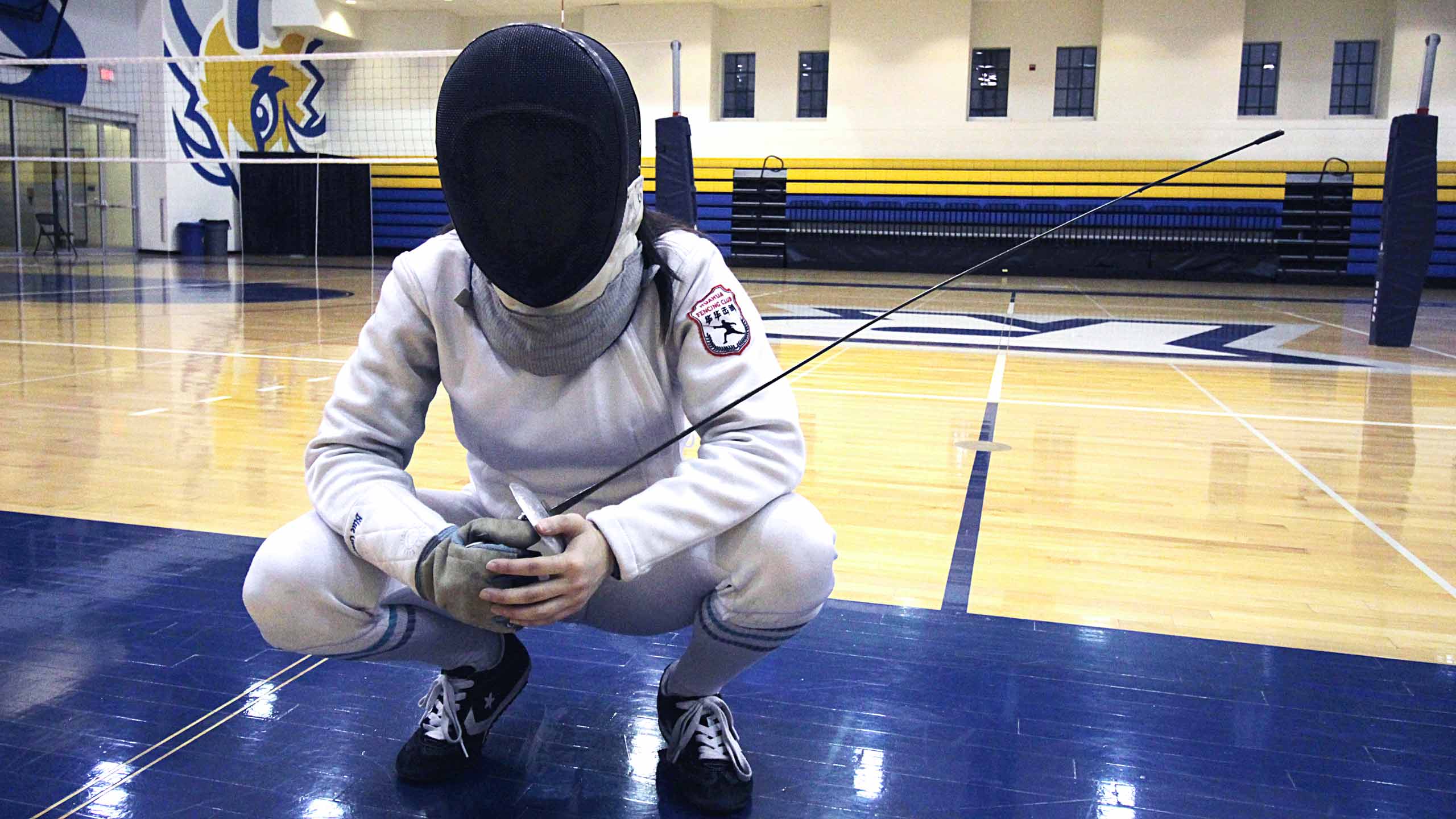 Fencer squatting with her sword