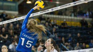Player Carabins blocks the volleyball as it goes over the net