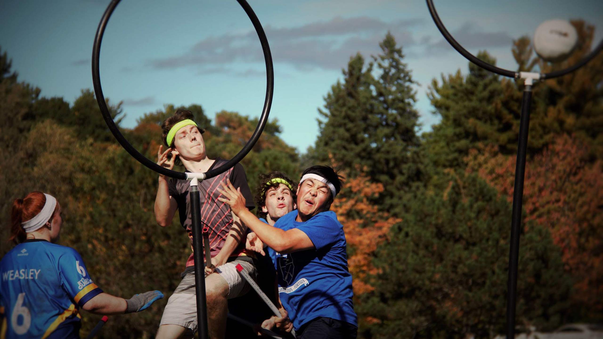 An epic shot of three quidditch players jumping up to hit a ball.