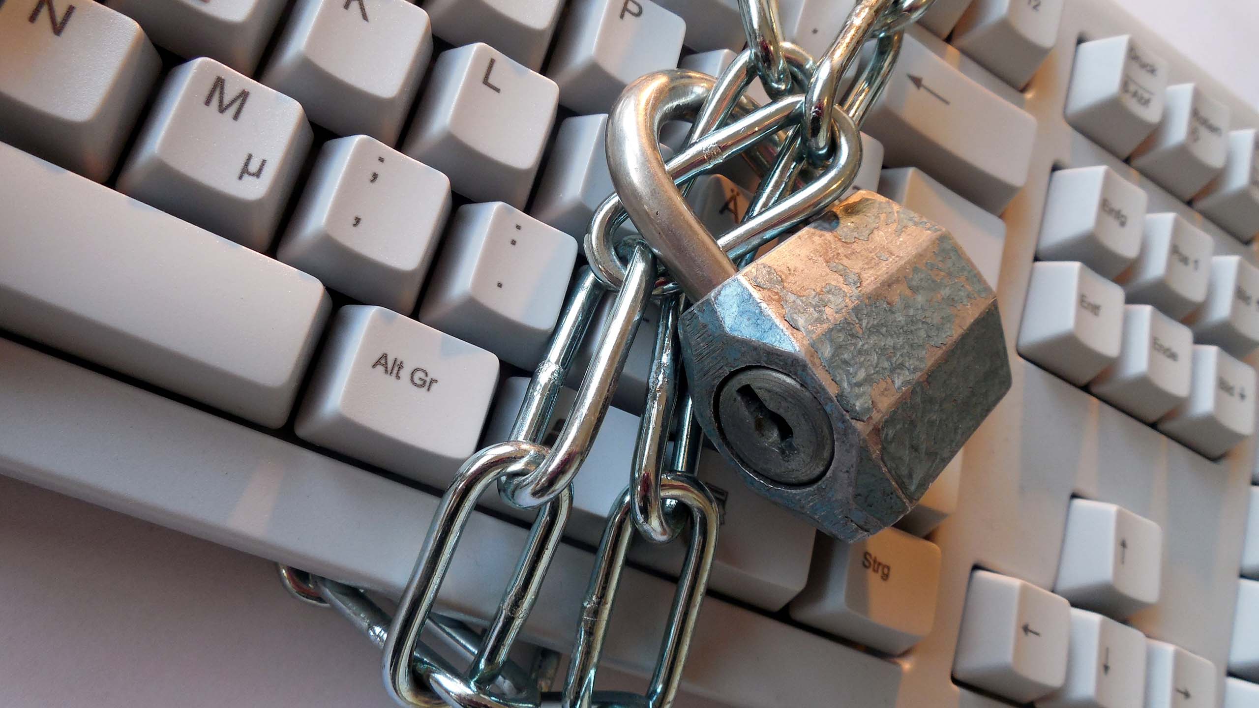 A padlock and chain wrapped around a keyboard.