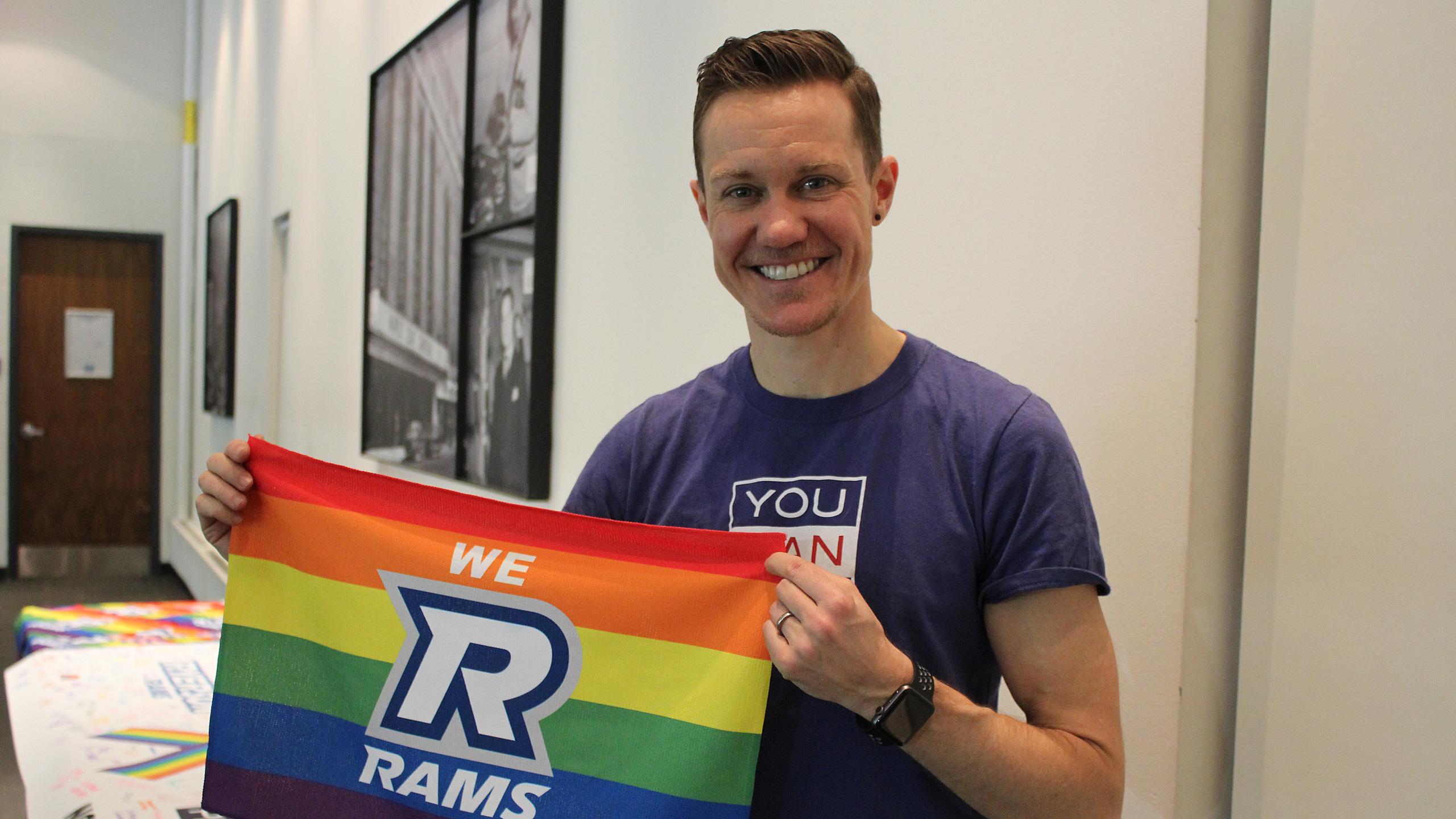 Chris Mosier poses with a we r rams rainbow flag