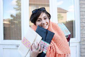 founder of the tight knit syria project holds knitted goods with a big smile on her face