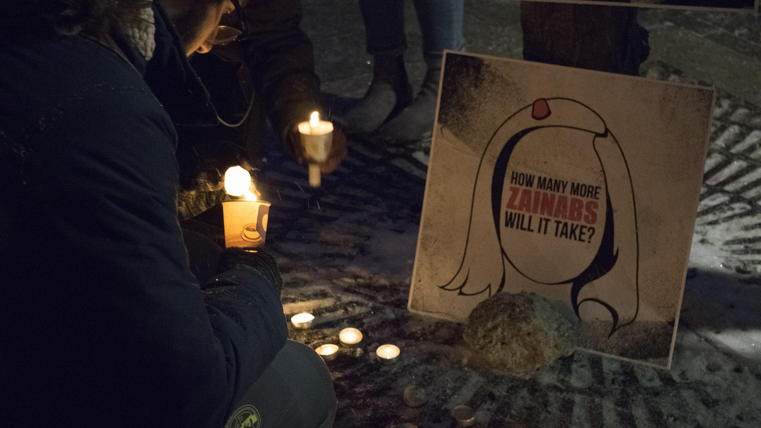 people holding candles, gathered around a sign captioned "how many Zainabs will it take?"