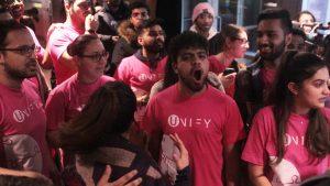 People in pink Unify t-shirts cheer