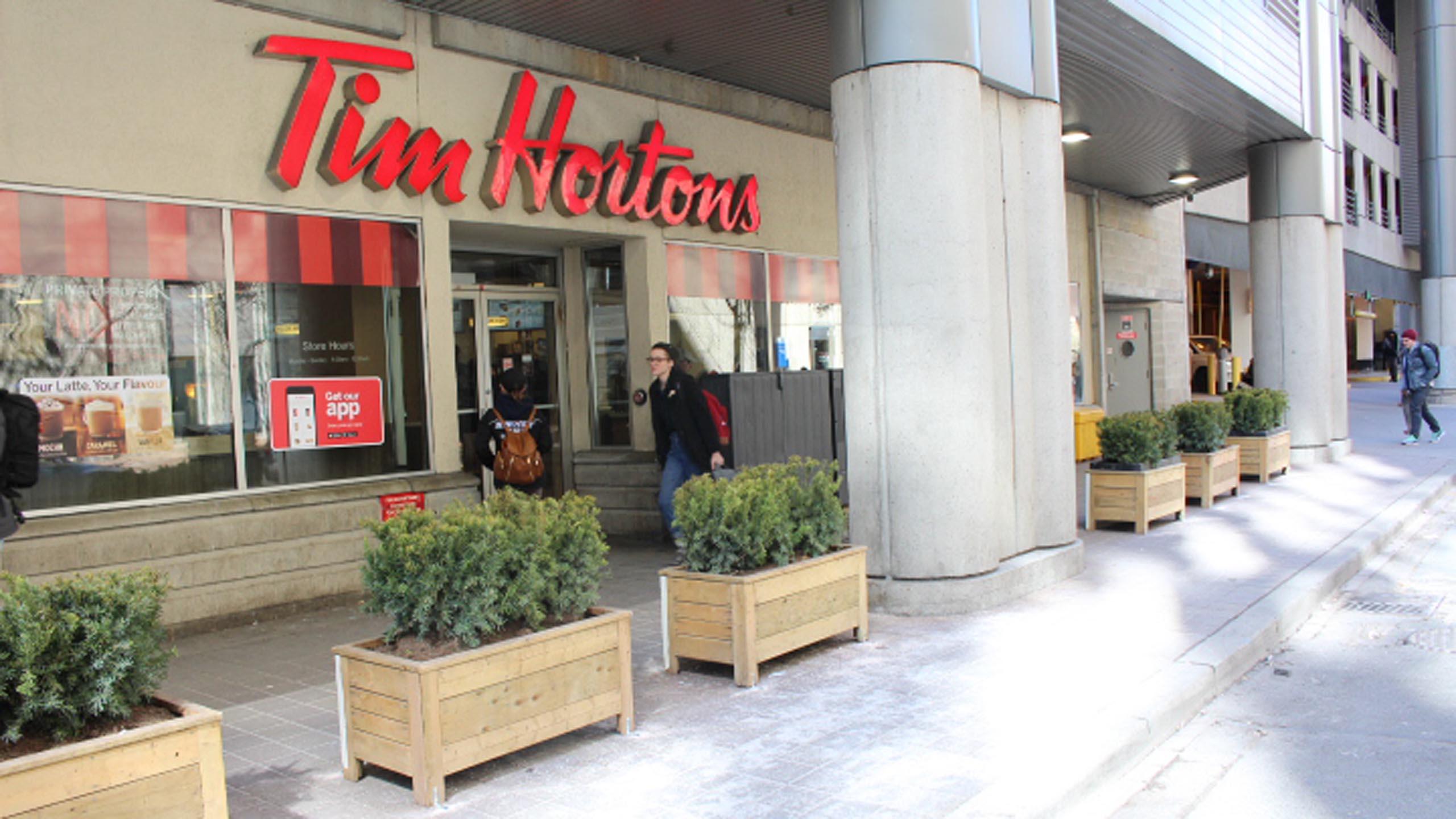 Potted planters alongside the curb in front of a Tim Hortons restaurant.
