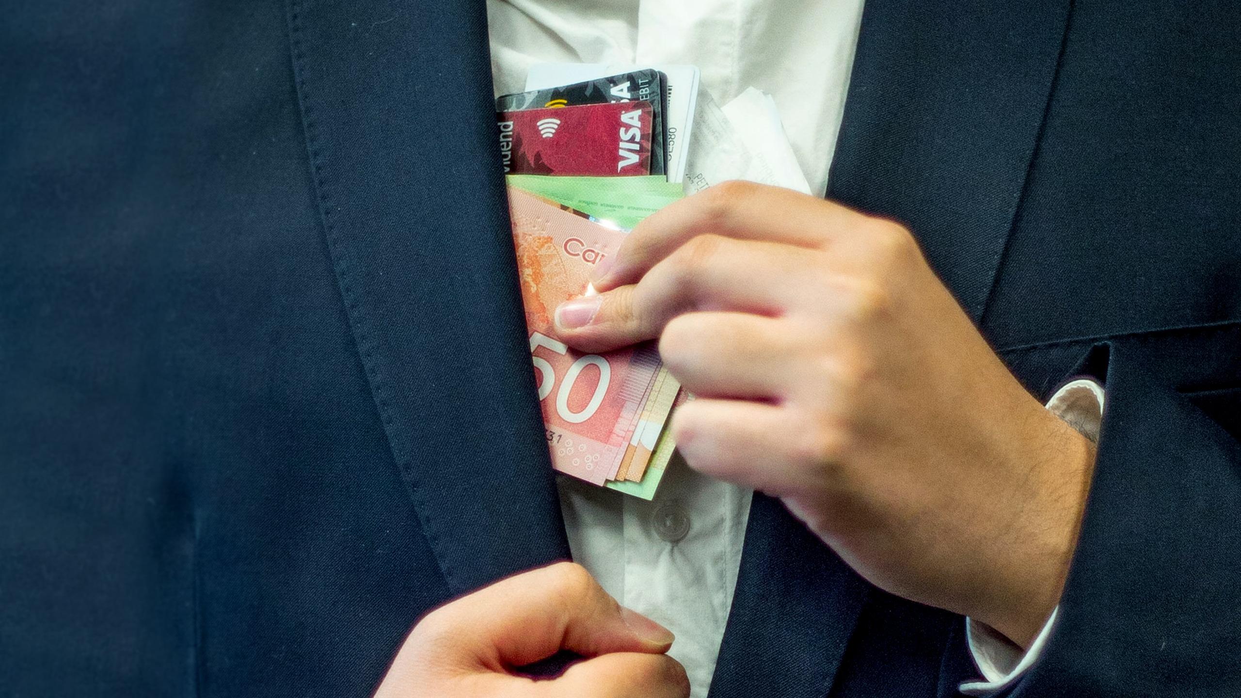 A man in a suit pockets credit cards and money.