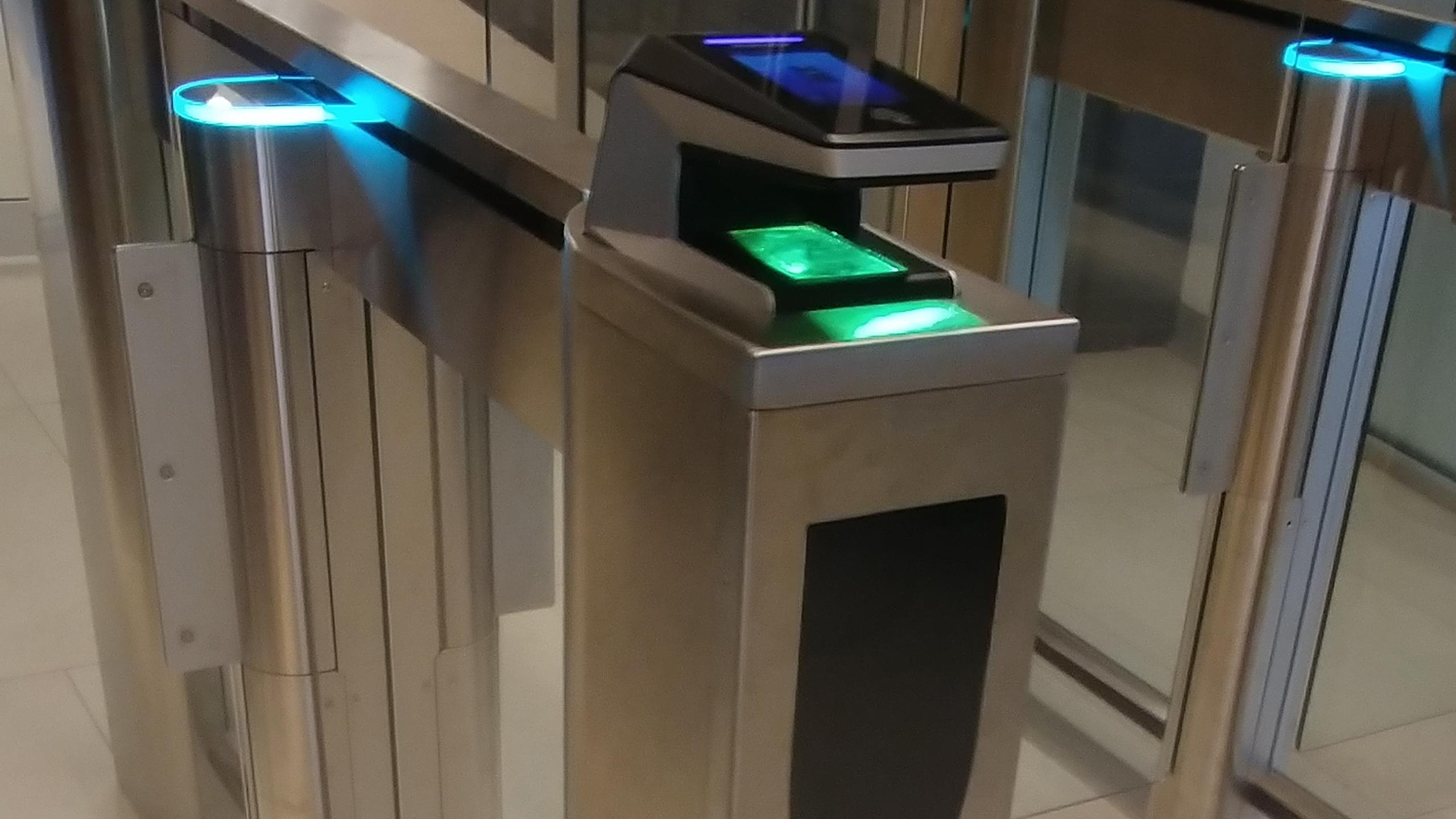 A photo of the biometric scanner in the HOEM building, a metal machine with a green and blue light scanner