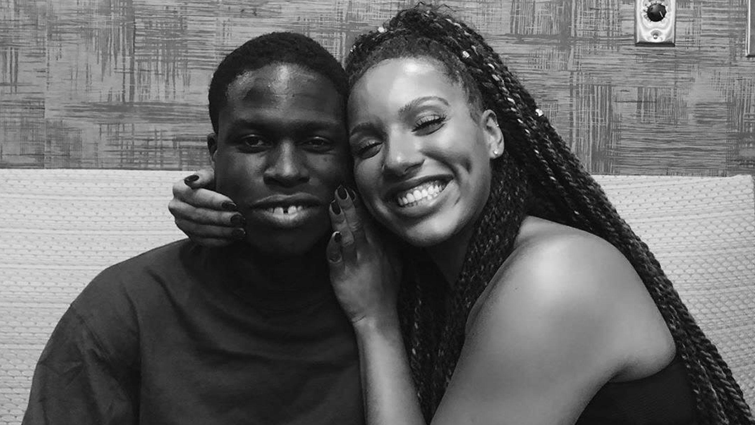 Elise Mariah Armstrong-Peart smiling with and embracing Daniel Caesar.