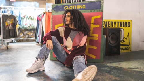 A person sits against a clothing sign in the Black Market