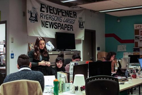 Photo of four Eye editors sitting at their desks, working on production in the office, SCC 207.