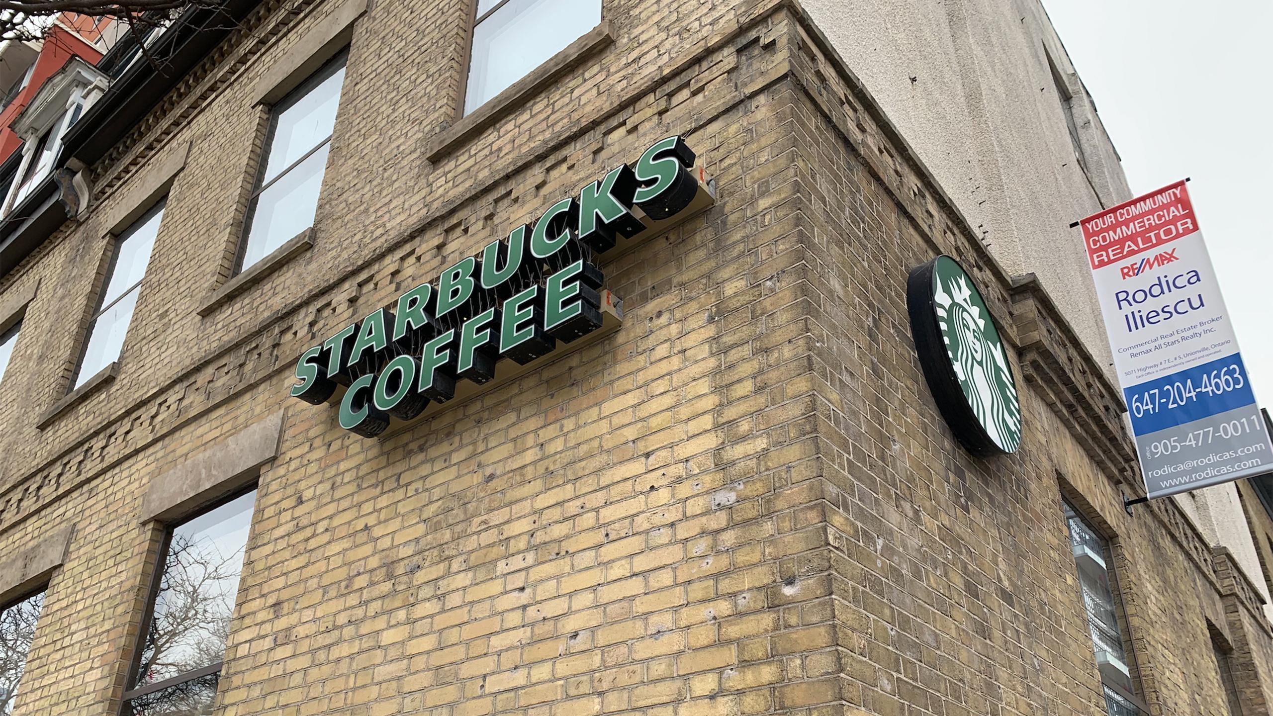 A Starbucks building with a realtor ad hanging on the wall.
