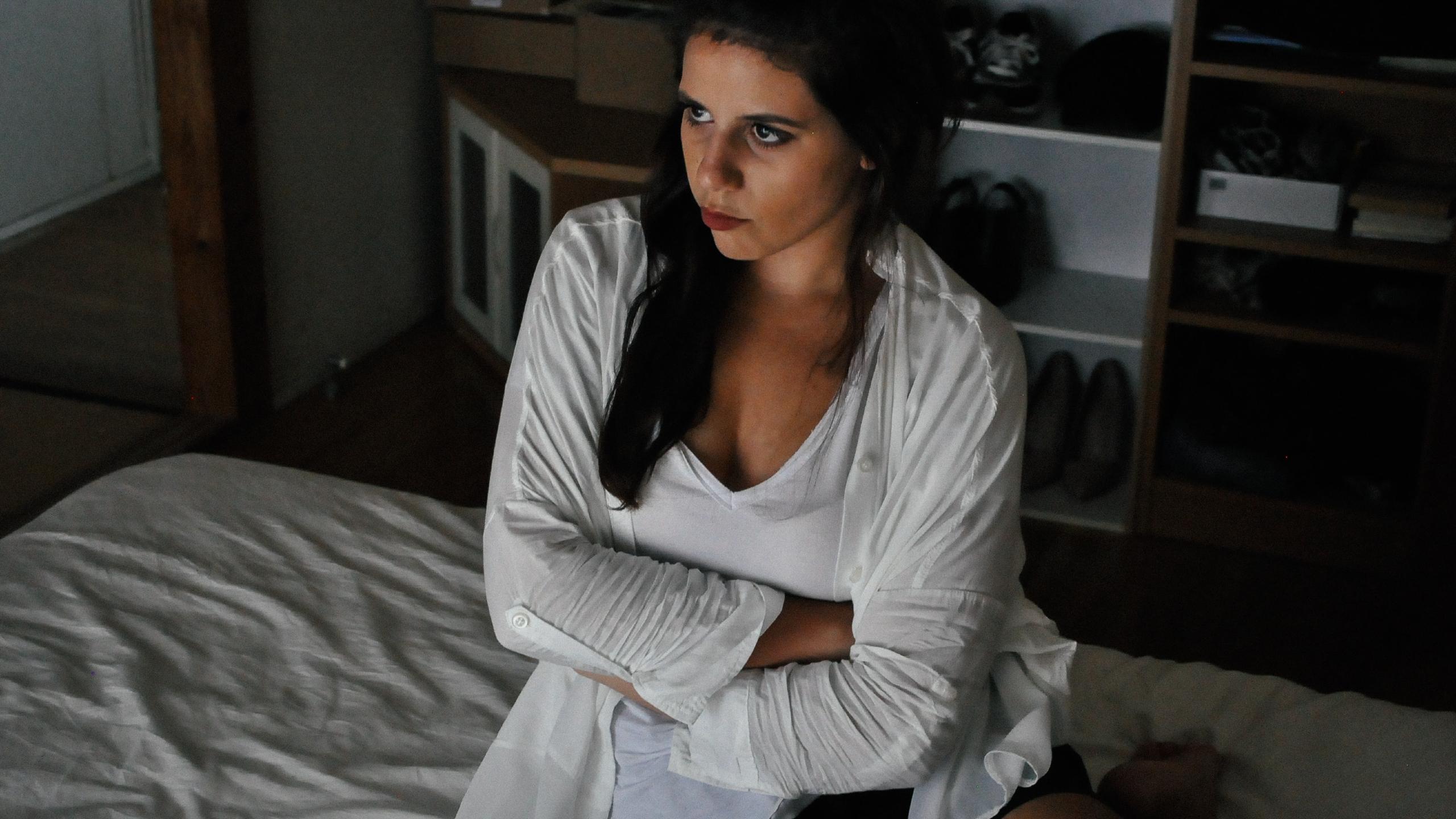 Woman sitting on a bed with her arms crossed looking frustratedWoman sitting on a bed with her arms crossed looking frustrated