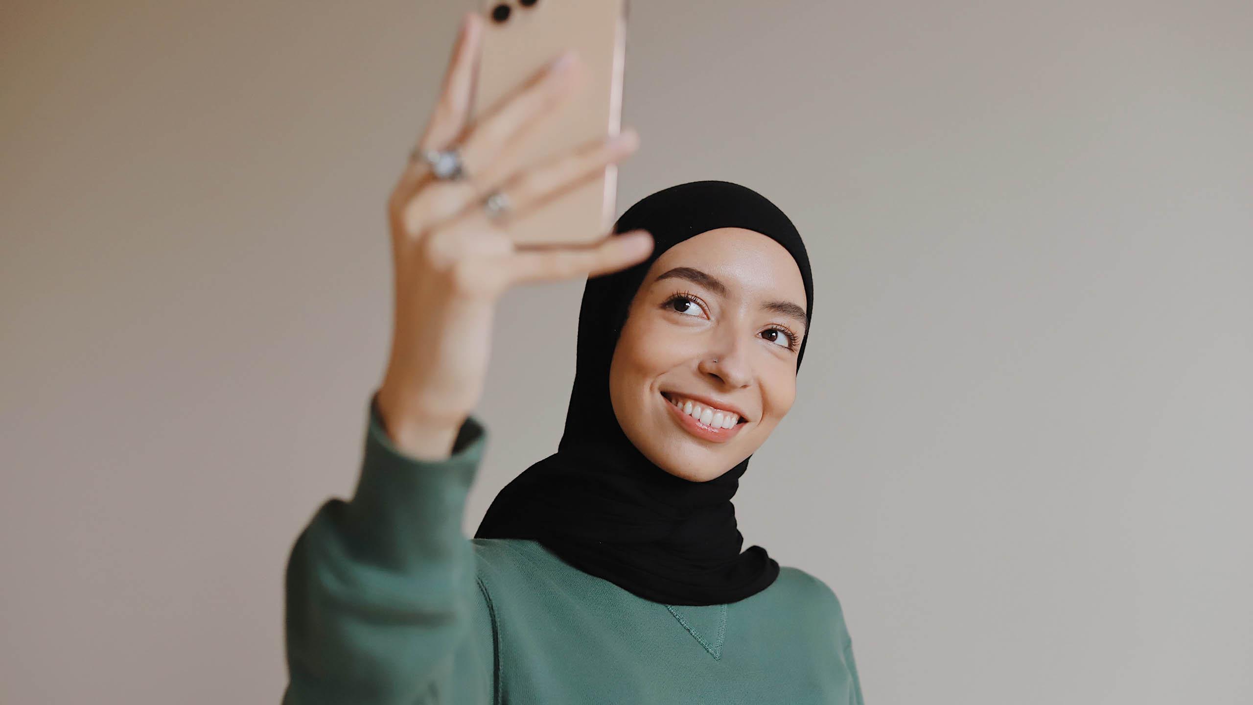 Hijabi girl taking selfie.