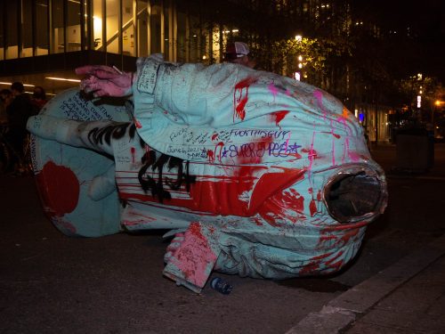 The decapitated Egerton Ryerson statue lying on Gould Street covered in red and pink paint and writing.