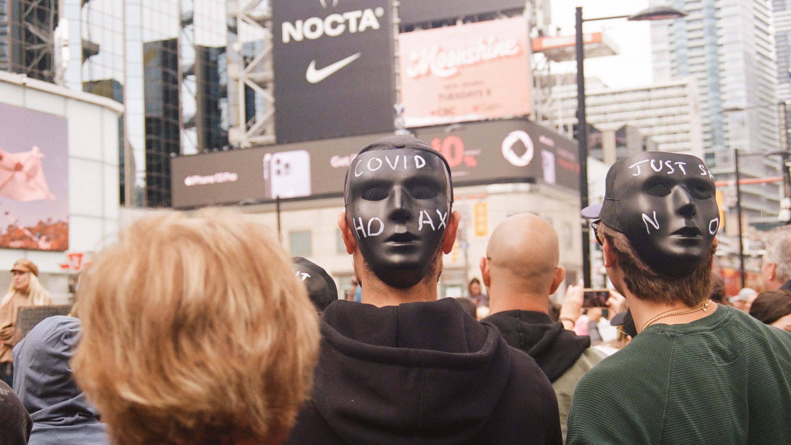 Demonstrators wear masks on the back of their heads during speeches at an anti-vaccine rally in Yonge-Dundas Square on Sept. 25.