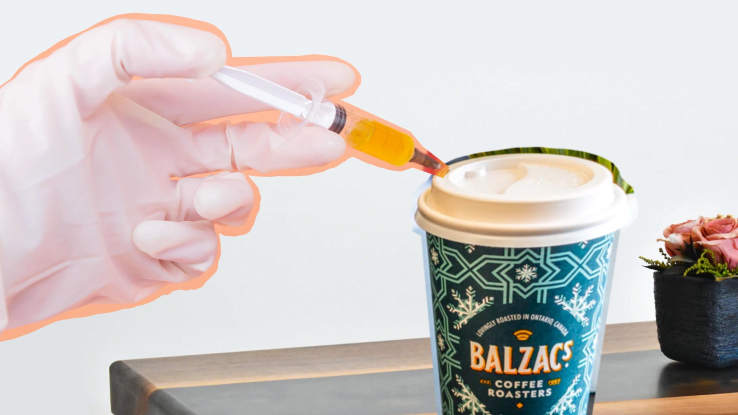 A gloved hand inserting a syringe into a Balzac's coffee cup
