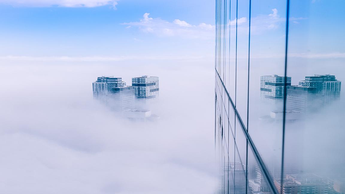 The top of a skyscraper poking through the clouds