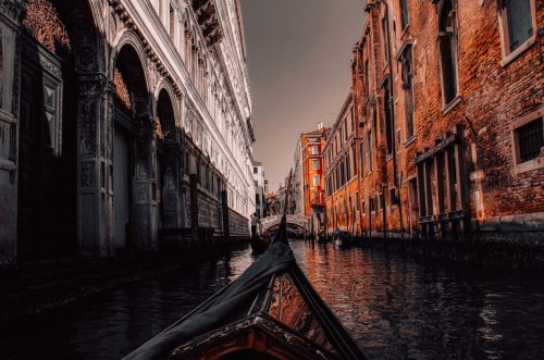 Stylized photo of a gondola in a river between old buildings