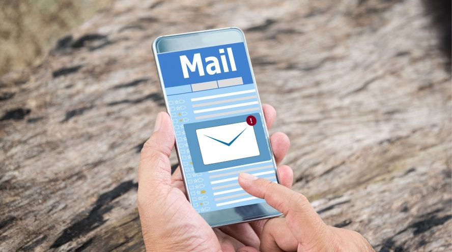 Person holding a phone with their emails open on the phone screen