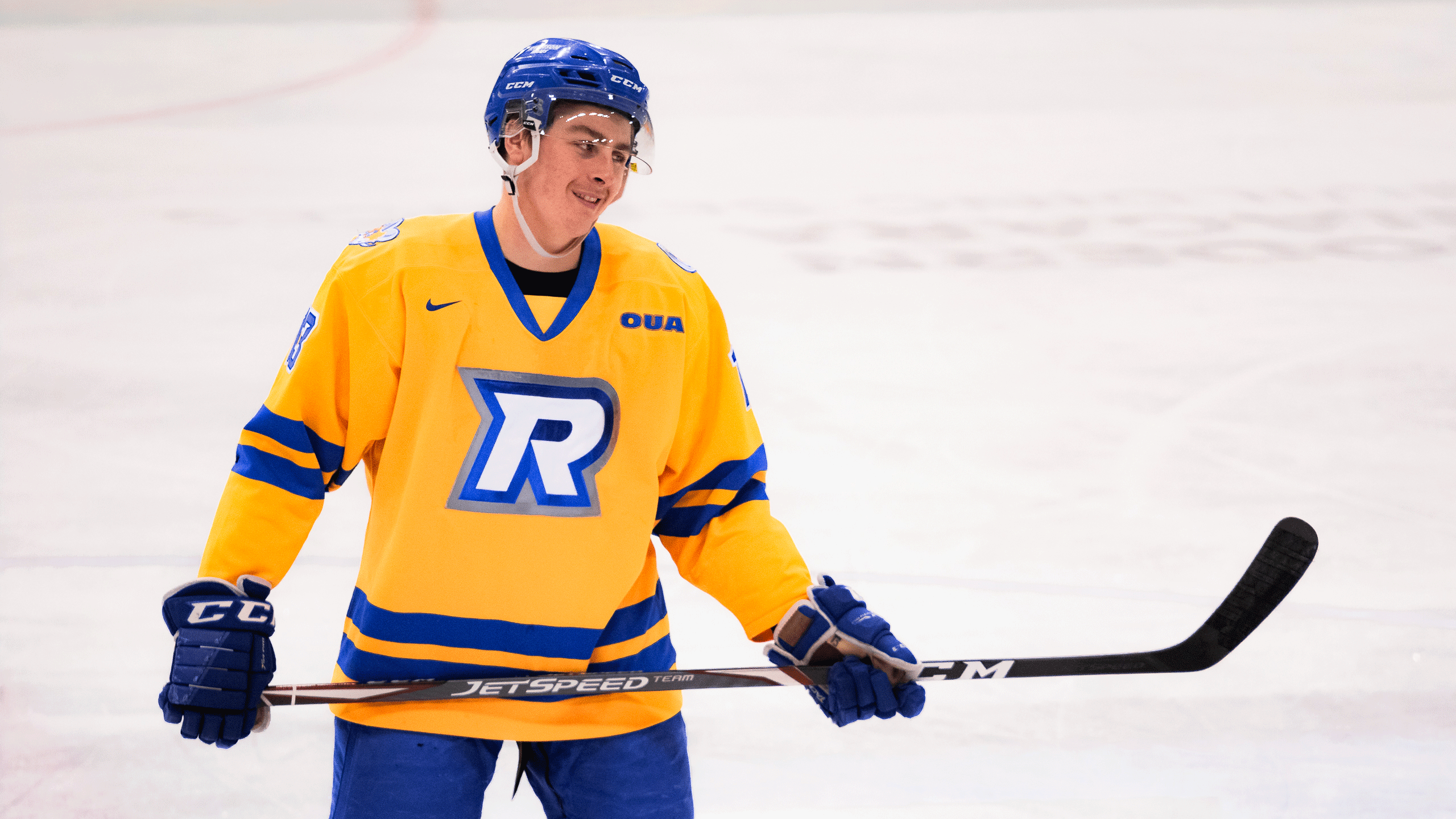 A Rams men's hockey player in a gold jersey smirks at his opponent