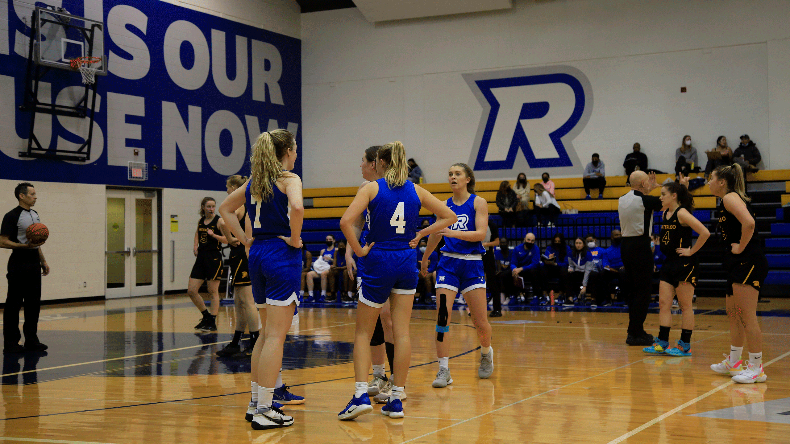 The Rams women's basketball team, in blue jerseys, have a discussion during a break in play