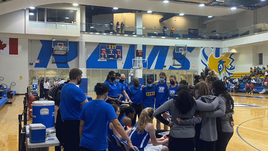 The Rams women's basketball team huddle together during a stoppage