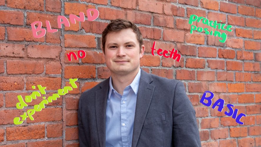 Man wearing suit and dress shirt standing in front of a wall. On the wall, the following words appear: bland, no teeth, don't experiment, practice posing, basic