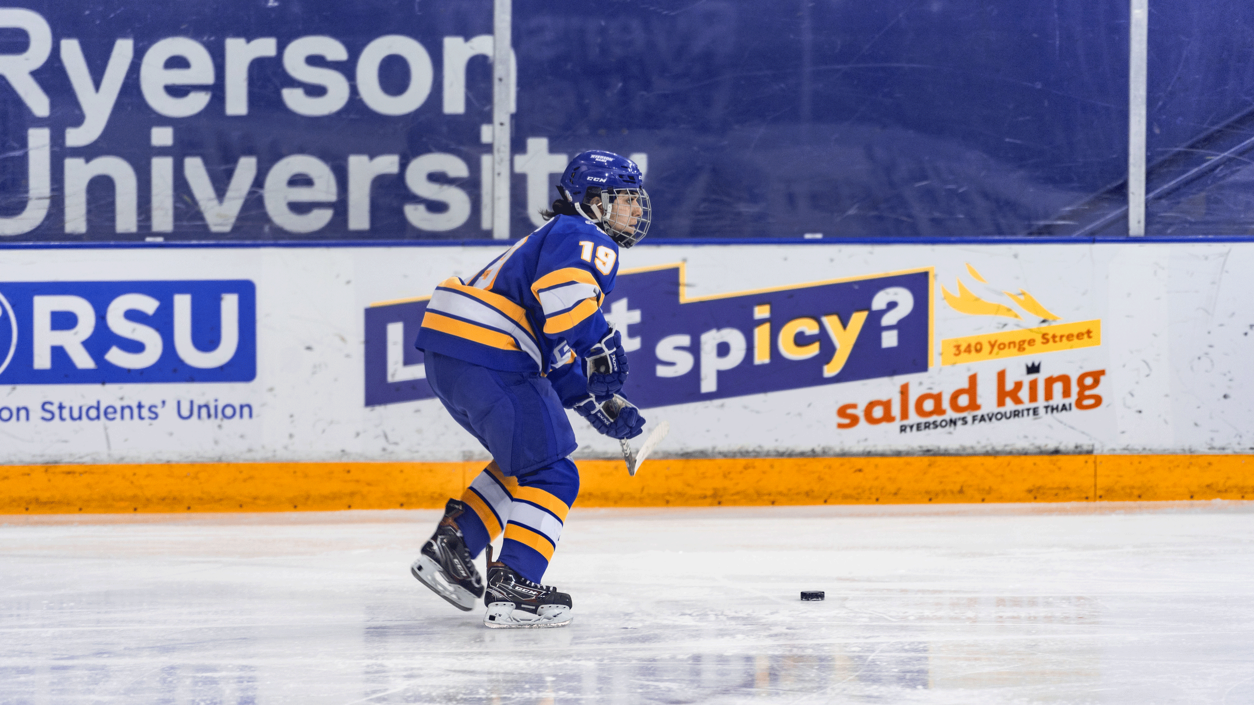 A Rams women's hockey player in a blue jersey surveys the ice
