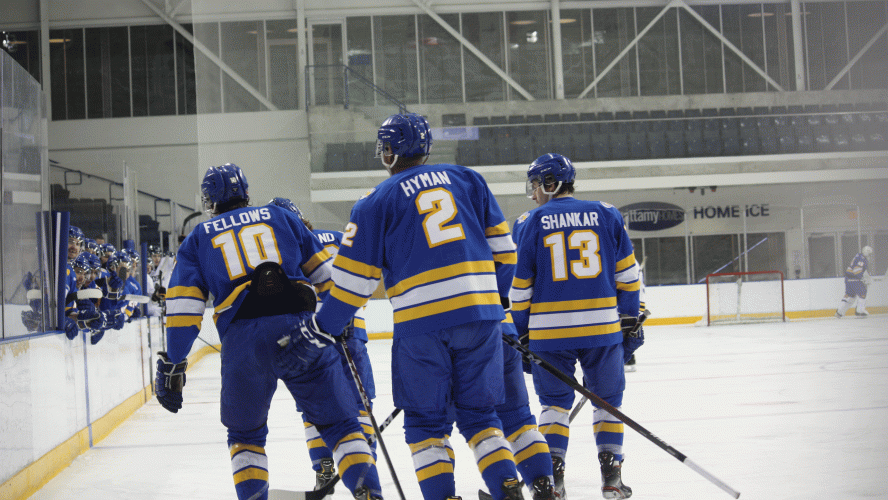 A trio of Rams men's hockey players in blue jerseys skate to the bench after a goal