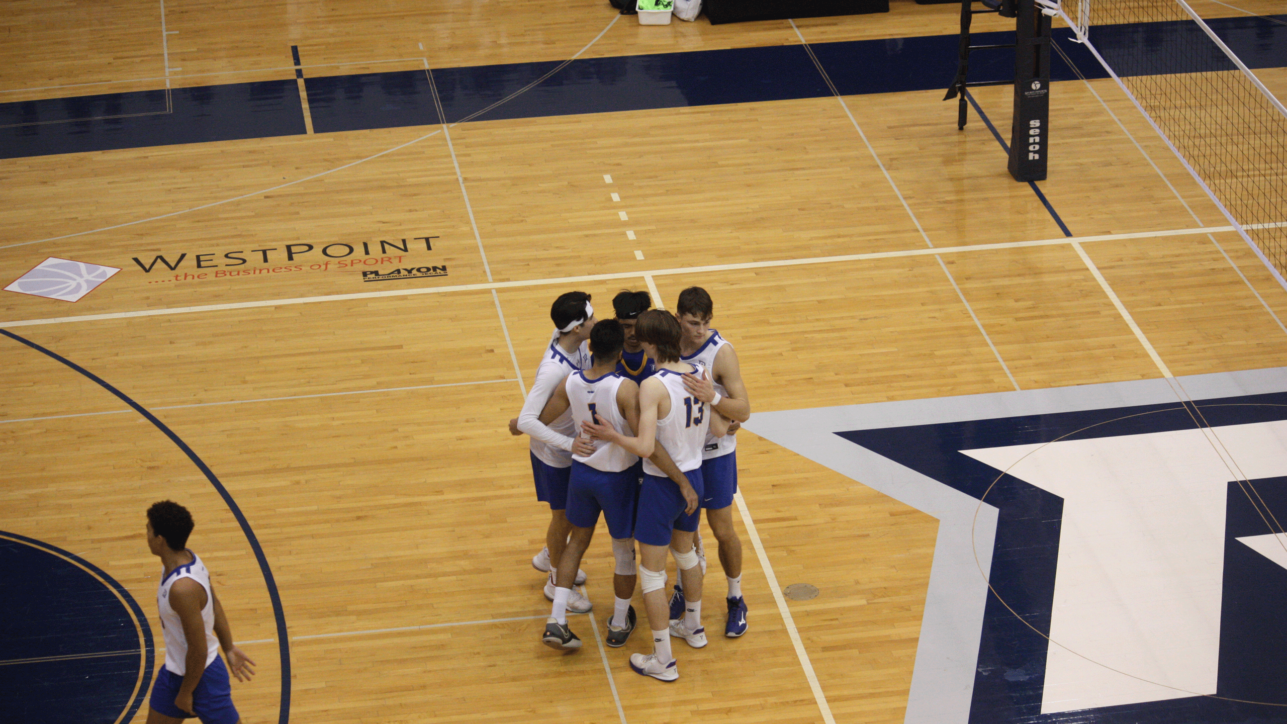 The Rams men's volleyball team in white jerseys celebrate their win