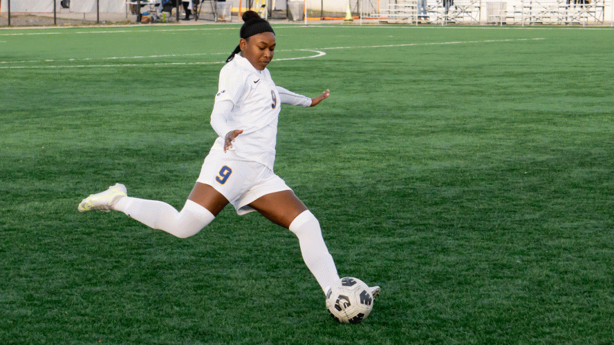 A Rams women's soccer player in a white jersey attacks the ball