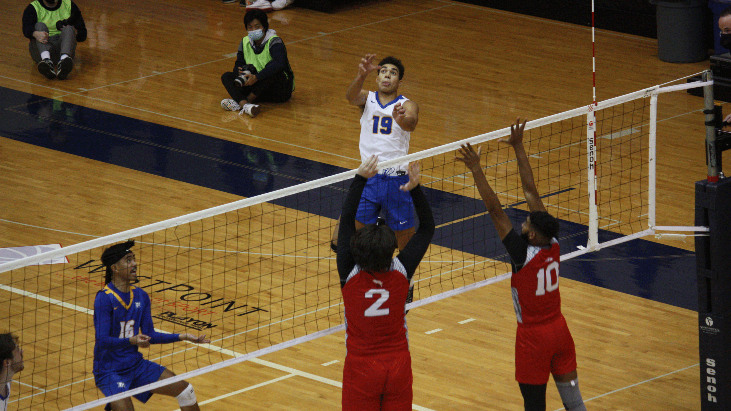 A Rams men's volleyball player in a white jersey goes for a kill