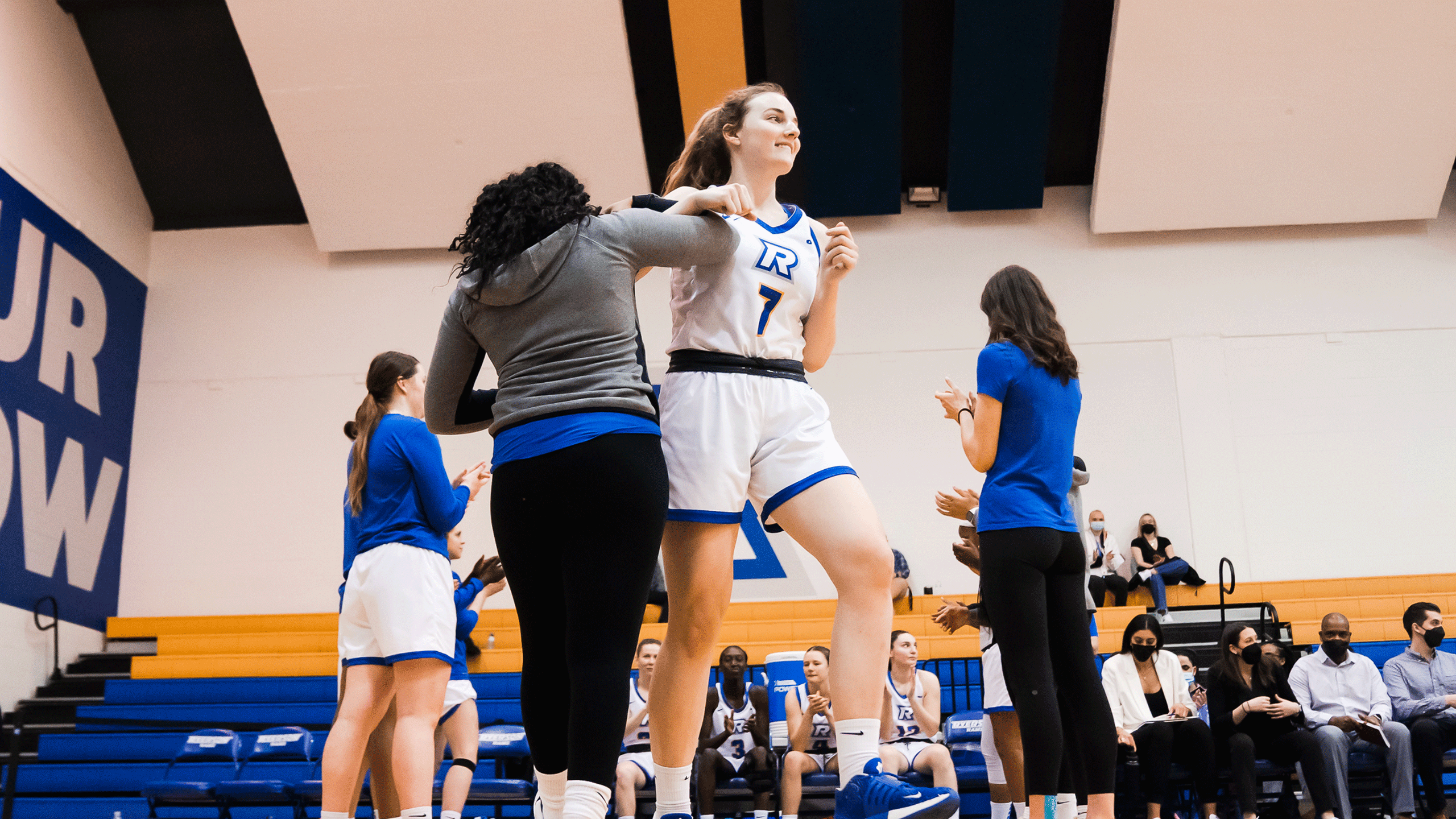 A Rams women's basketball player in a white jersey celebrates
