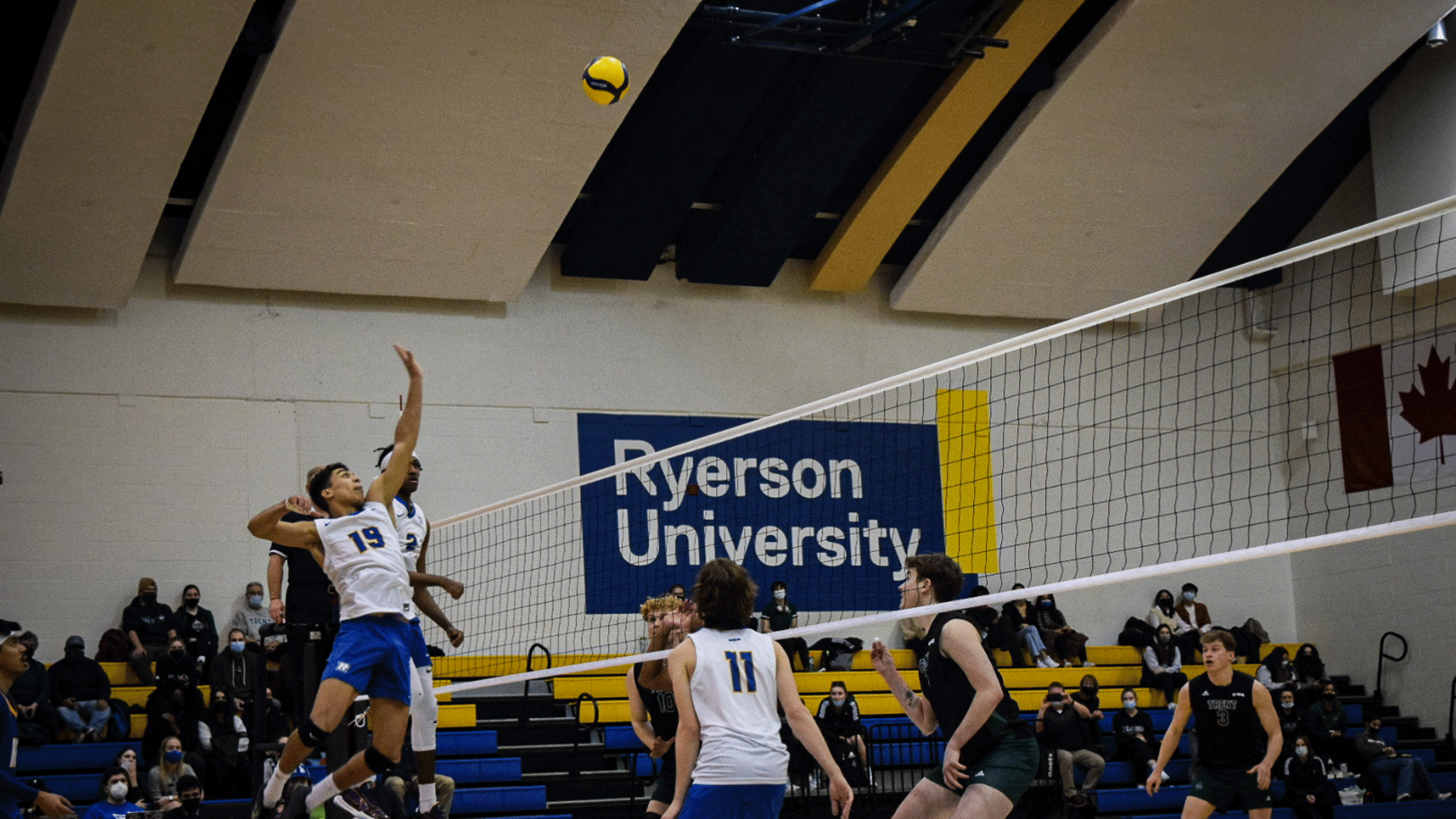 A Rams men's volleyball player in a white jersey flys through the air