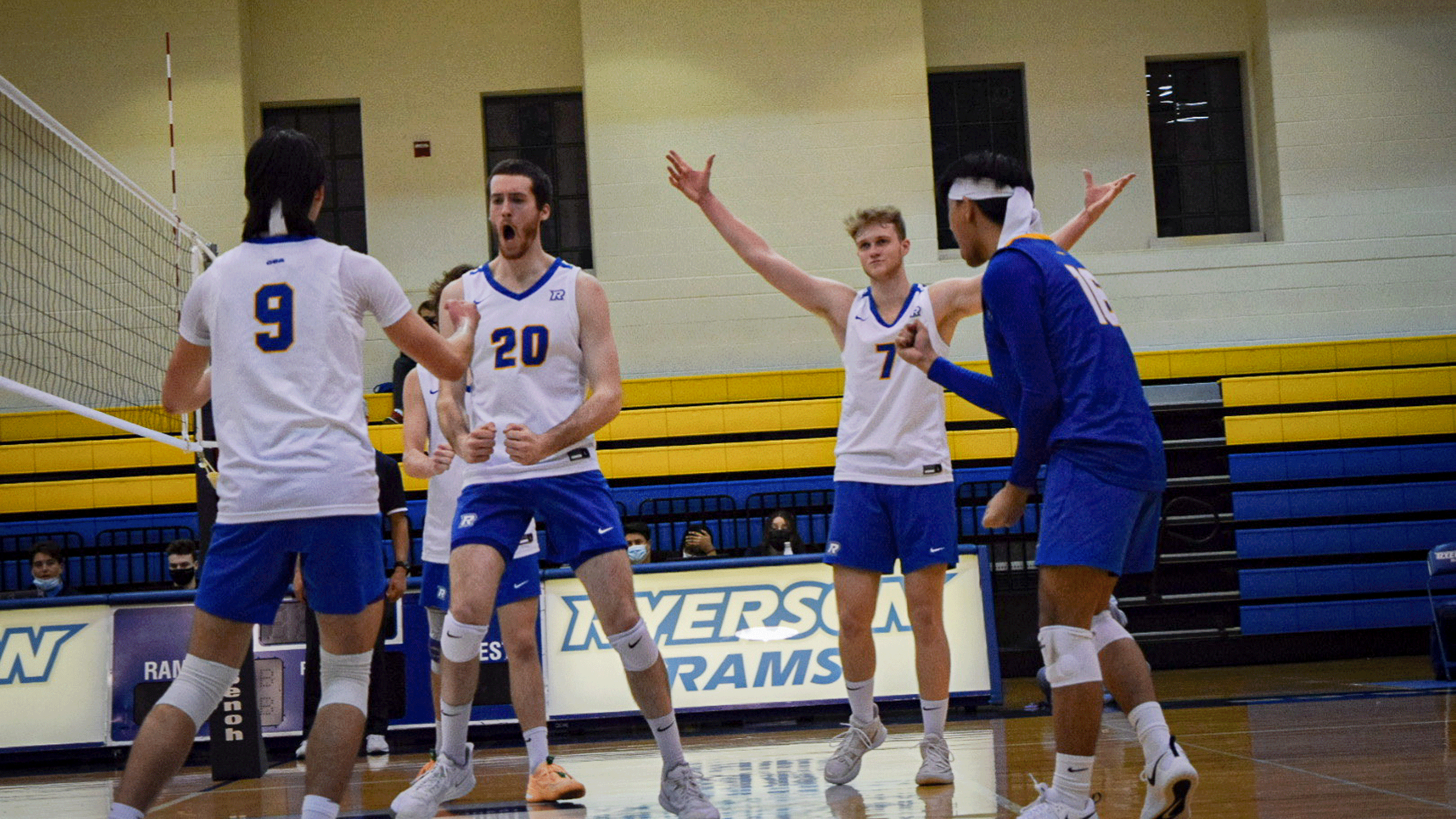 The Rams men's volleyball team in white jerseys celebrate a win