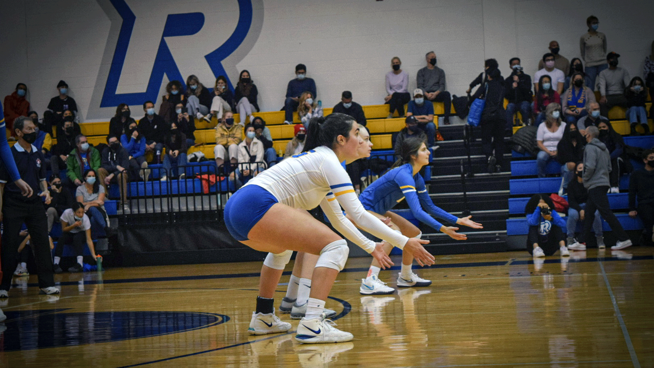 A Rams women's volleyball player in a white jersey waits for the ball