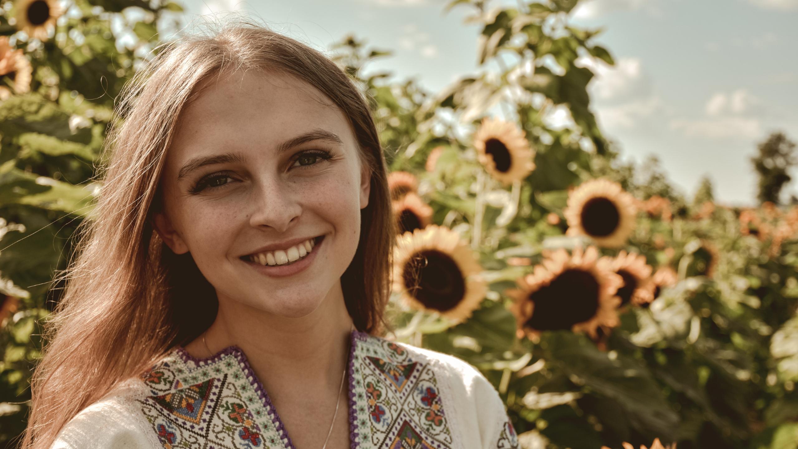 Alexandra Holyk in front of a sunflower field.