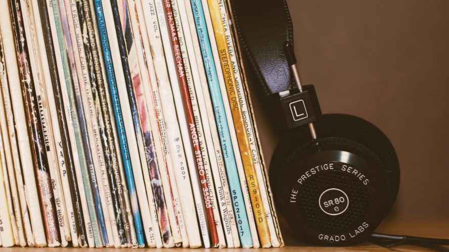 Photo of black headphones leaning against a stack of records