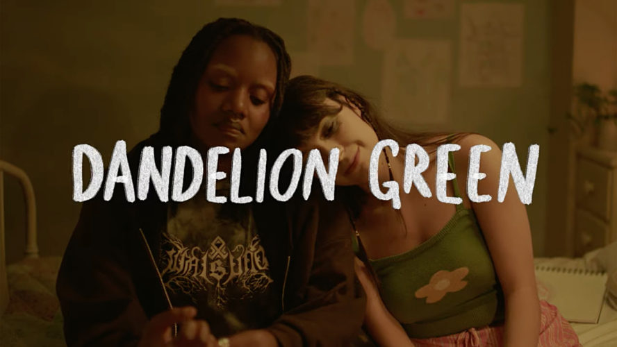 Two teenagers sitting on a bed. The person on the right is leaning their head on the person on the left's shoulder. White text reading "Dandelion Green."