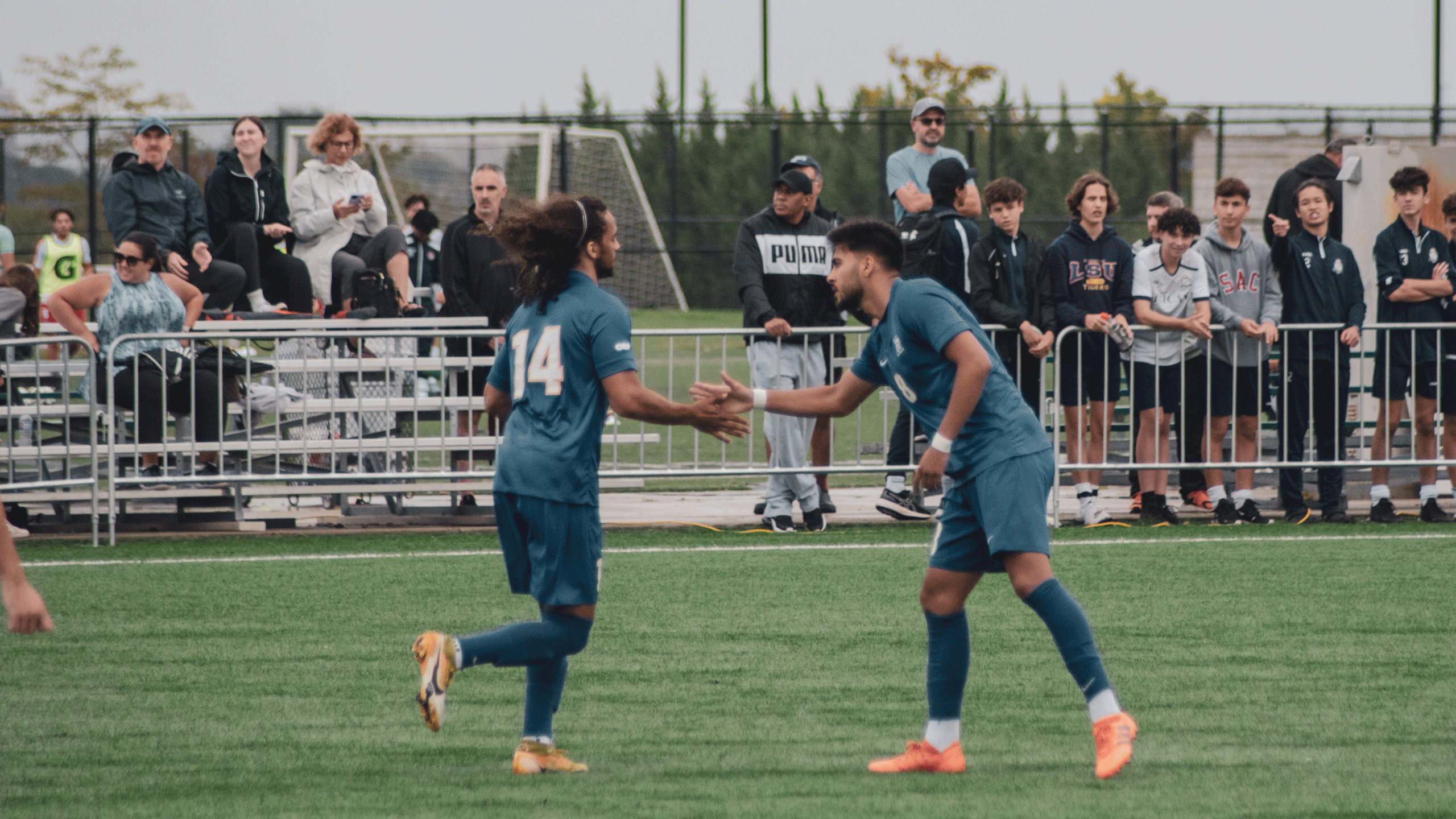 A pair of soccer players in blue jerseys shake hands