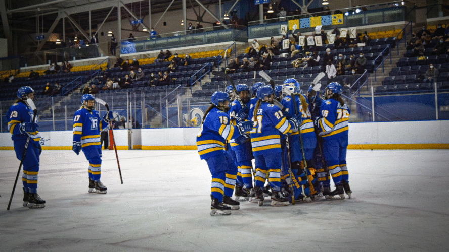 A hockey team in blue jerseys huddle after winning a game