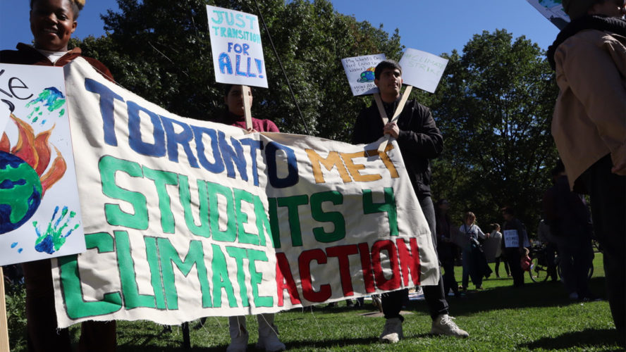 Students stand outside holding picket signs and a banner that reads "Toronto Met Students 4 Climate Action"