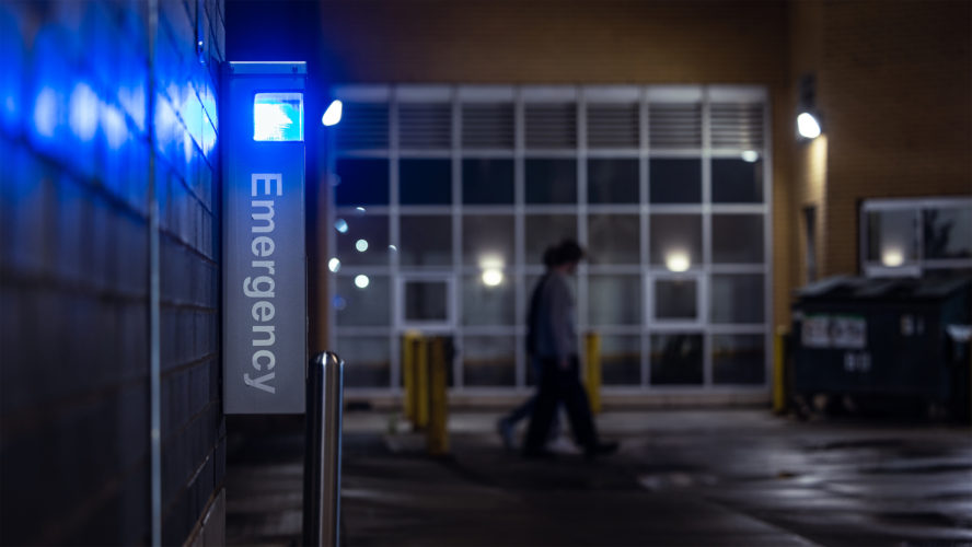 A glowing blue emergency assistance pole on campus