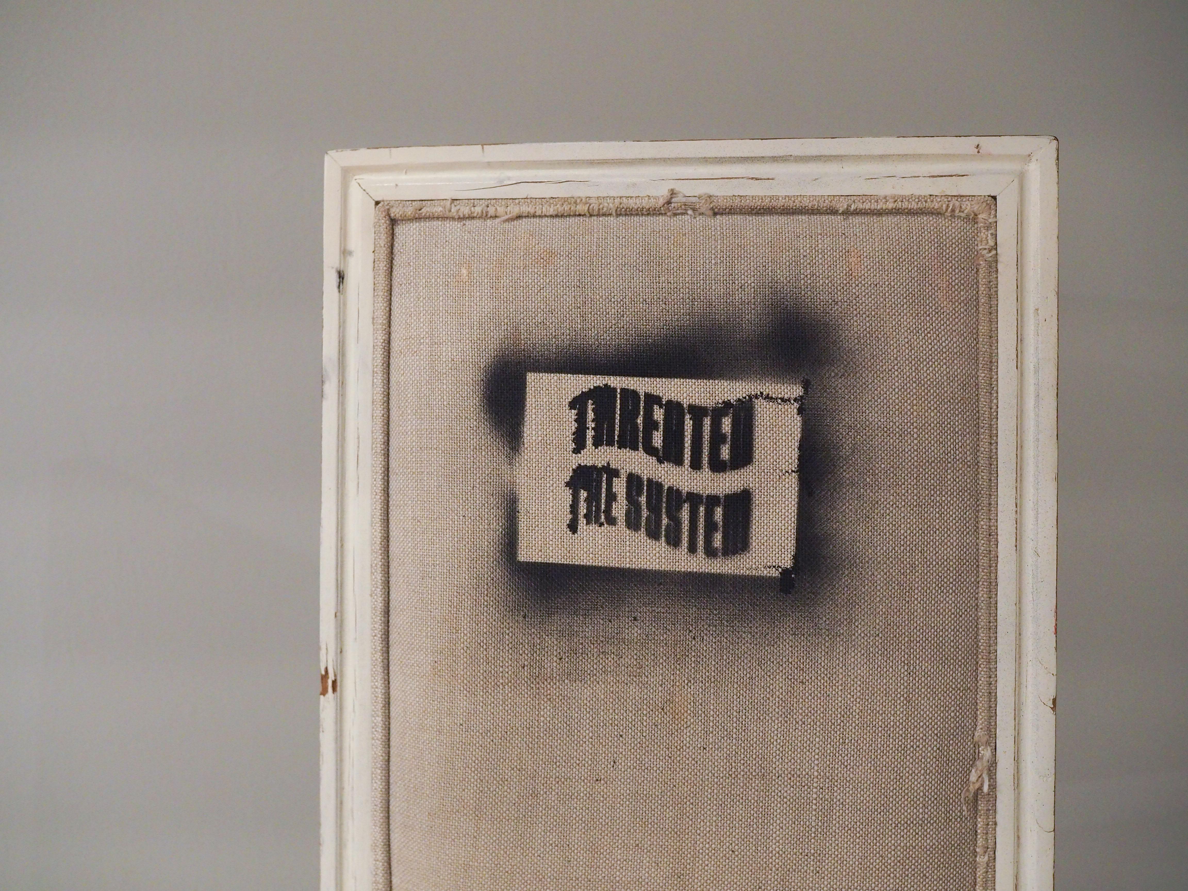 A chair spray painted with a stencil that reads "THREATEN THE SYSTEM""
