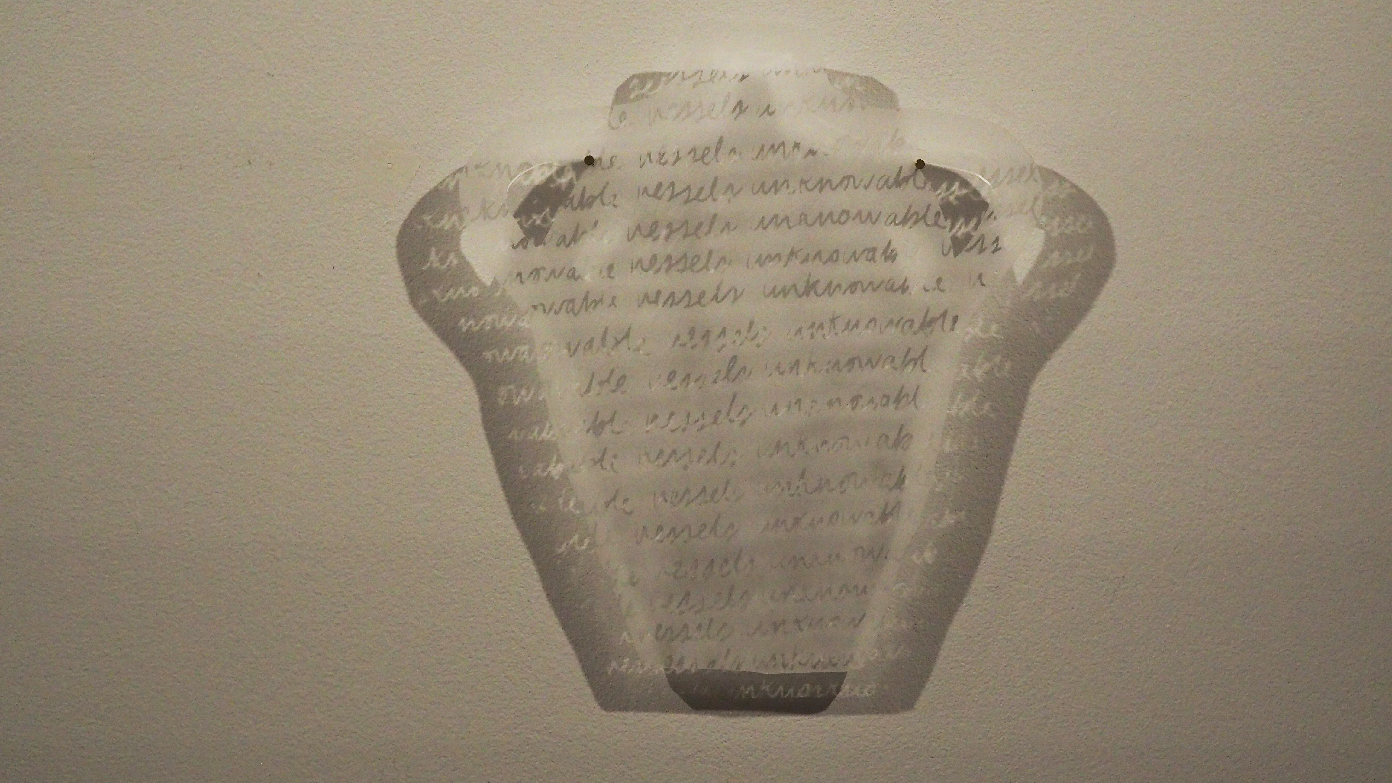 A wall-mounted acrylic plastic silhouette of a pot with cursive script on it that reads "vessels unknown"